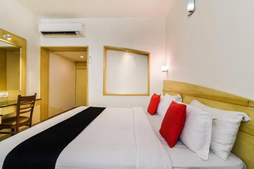 una camera da letto con un grande letto bianco con cuscini rossi di Super Capital O Hotel Grand Plaza a Coimbatore