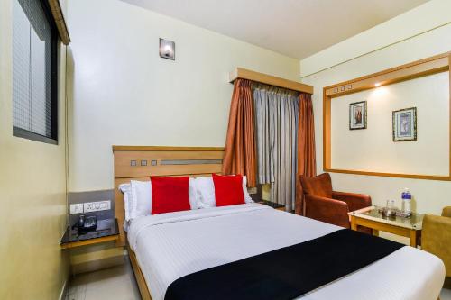 a hotel room with a bed and a desk and a chair at Super Capital O Hotel Grand Plaza in Coimbatore