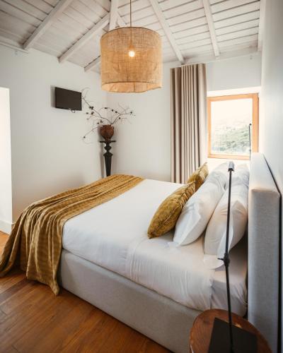 a bedroom with a bed with white sheets and a window at Cerquido by NHôme in Cerquido