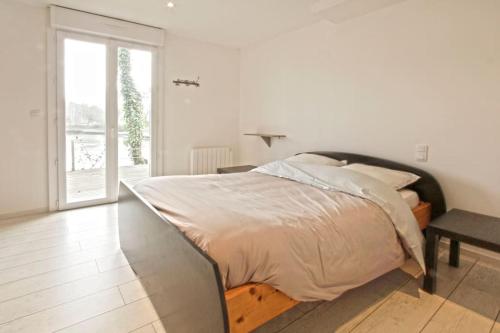 a white bedroom with a large bed and a table at gite au calme au coeur du vignoble Nantais 