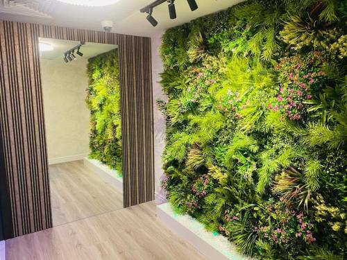 ein Zimmer mit einer grünen Wand mit Pflanzen und Blumen in der Unterkunft The sunset haven in Dubai
