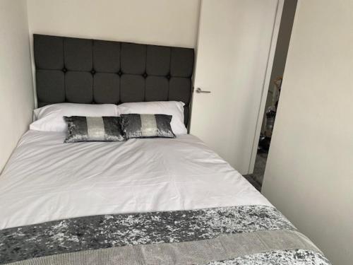 a large bed with a black headboard and two pillows at Manchester Home near Near City center and Stadium in Manchester