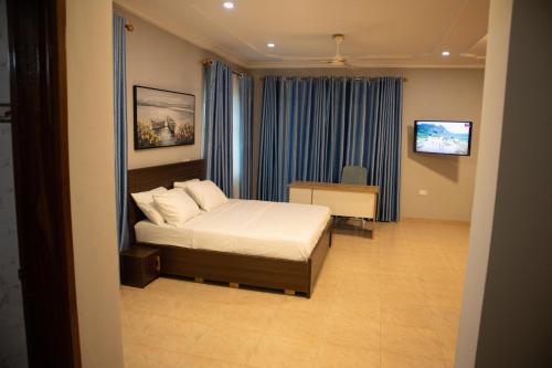 a bedroom with a bed and a desk and a television at EXECUTIVE MASTER BEDROOM in Accra