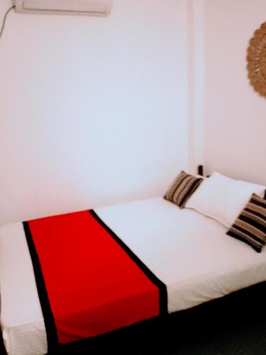 a red and white bed in a white bedroom at Area 51 Apartment in Mirissa