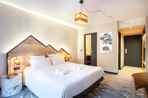 a bedroom with a large white bed in a room at Hotel Base Camp Lodge - Albertville in Albertville