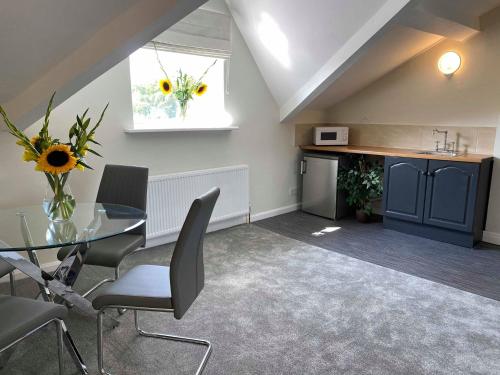 a dining room with a glass table and a kitchen at The Sitwell Arms Hotel in Mosborough