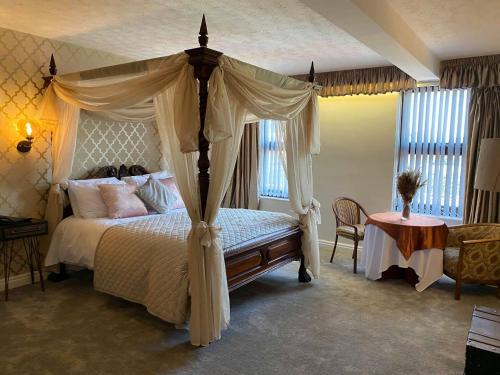 a bedroom with a canopy bed and a table at The Sitwell Arms Hotel in Mosborough