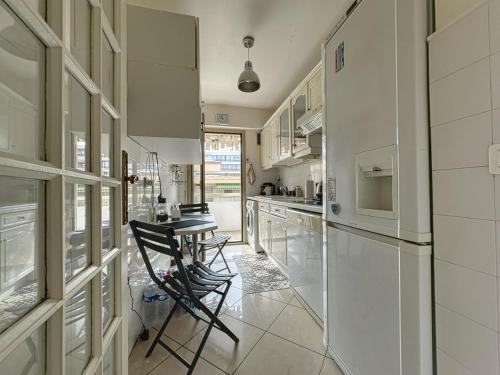 - une cuisine avec des appareils blancs, une table et des chaises dans l'établissement Appartement proche CARLTON, à Cannes