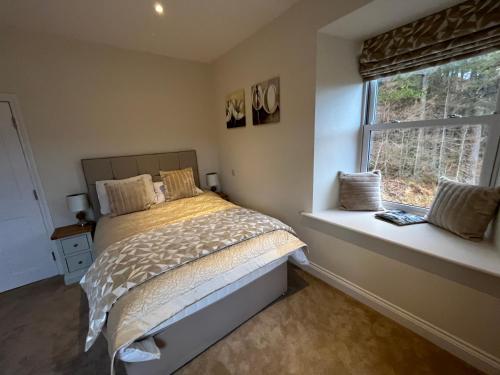 a bedroom with a bed sitting next to a window at Tomdoun Estate in Invergarry