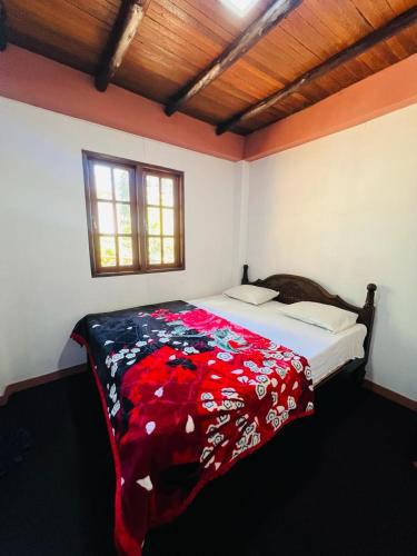 a bedroom with a bed with a red blanket on it at Micro wood cabana in Nuwara Eliya