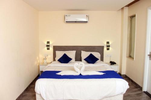 a bedroom with a large white bed with blue pillows at Alegria Resort and SPA, Kovalam in Tirupporūr