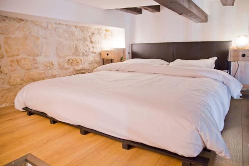 - un grand lit blanc dans une chambre dotée d'un mur en pierre dans l'établissement Modern Loft Saint Germain Luxembourg Odéon, à Paris