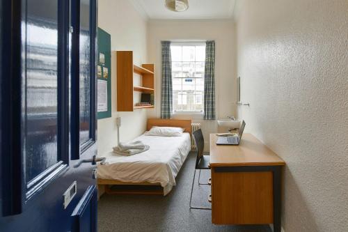 Cette chambre comprend un lit et un bureau avec un ordinateur portable. dans l'établissement Campbell House, à Londres