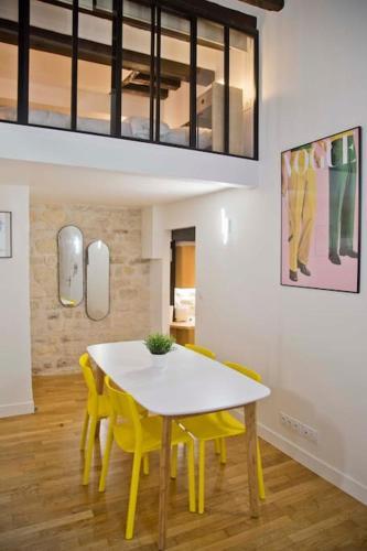 une salle à manger avec une table blanche et des chaises jaunes dans l'établissement Modern Loft Saint Germain Luxembourg Odéon, à Paris