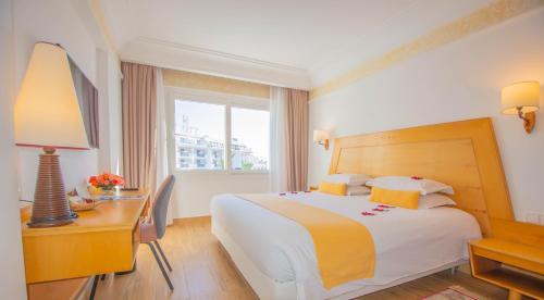 a hotel room with a bed and a desk and a window at Hotel Timoulay and Spa Agadir in Agadir