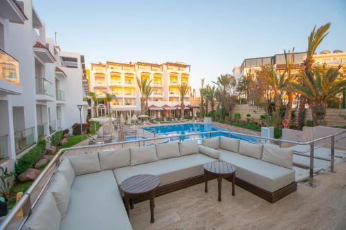 a balcony with a couch and a swimming pool at Hotel Timoulay and Spa Agadir in Agadir