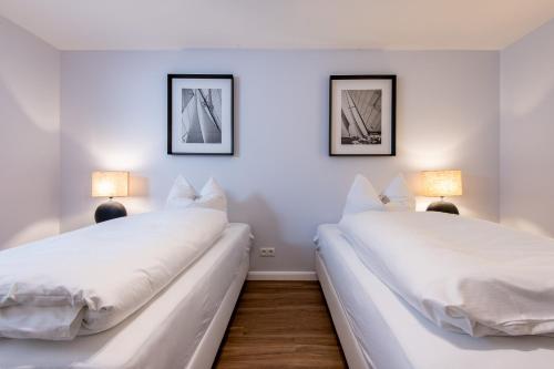 2 weiße Betten in einem Zimmer mit 2 Lampen in der Unterkunft Erich Johannsen Wai Whg 4 in Keitum