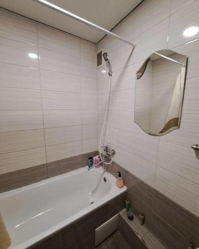 a bathroom with a bath tub and a mirror at Студия 2 комнаты в центре города in Kryvyi Rih