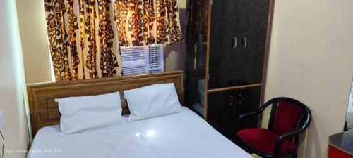 a bedroom with a bed and a red chair at Hotel JM International (A Unit of Hotel Care Plaza) in Puri