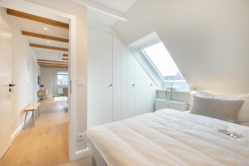 um quarto branco com uma cama grande e uma janela em Strandbude Sylt em Westerland