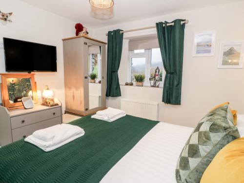 een slaapkamer met een bed met een groene deken bij Cwm Caeth Cottage in Caernarfon