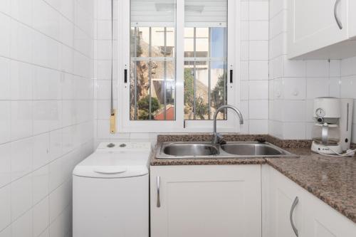 a white kitchen with a sink and a window at Hawai Bajo in Faro de Cullera