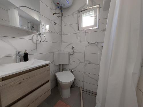 a bathroom with a toilet and a sink and a window at Apartments Timee first row to beach in Stanići