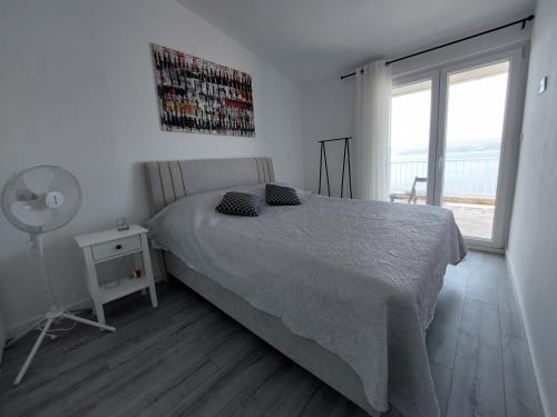a bedroom with a bed and a fan and a window at Apartments Timee first row to beach in Stanići