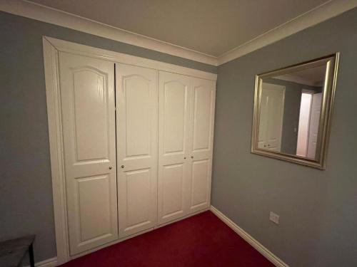 a bedroom with white closet doors and a mirror at Room 5 - Chassagne Guest House in Church Coppenhall