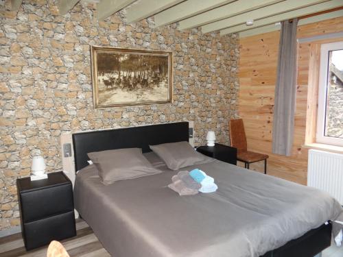 1 dormitorio con cama y pared de piedra en B&B Le bruissement en Bièvre