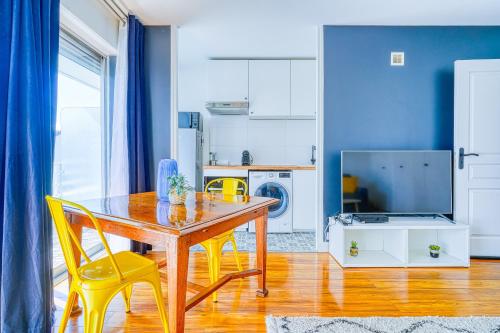uma sala de jantar com uma mesa de madeira e cadeiras amarelas em Studio cosy et calme au 1er étage avec balcon à 15 min du RER A em Fontenay-sous-Bois