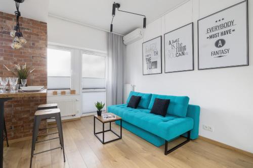 Turquoise Studio with Balcony & Air Conditioning Kraków by Renters في كراكوف: غرفة معيشة مع أريكة زرقاء وجدار من الطوب