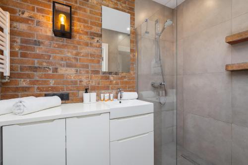 a bathroom with a white sink and a brick wall at Turquoise Studio with Balcony & Air Conditioning Kraków by Renters in Krakow
