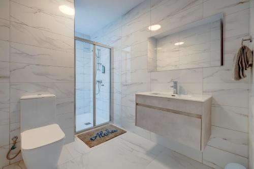 a white bathroom with a toilet and a sink at Salmar Court Holiday Apartments in Hal Ghaxiak