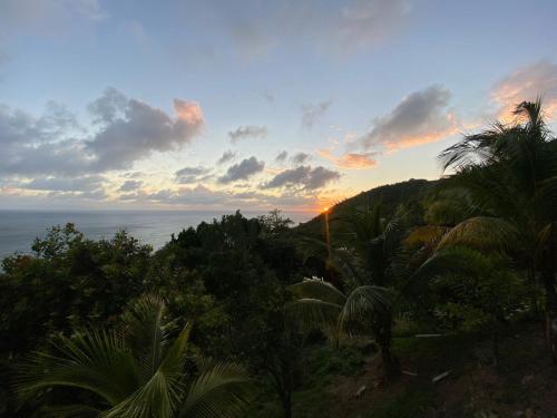 a sunset over the ocean with palm trees on a hill at LE BLANC HIDEAWAY in Laborie