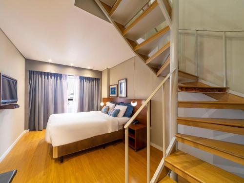 a bedroom with a bed and a staircase at Mercure Curitiba Golden in Curitiba