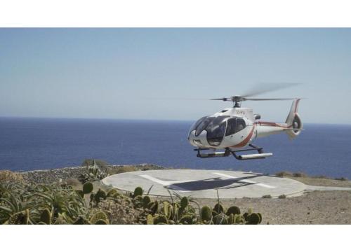 a small helicopter is flying over the ocean at Blueros Luxury Villa in Megas Yialos-Nites