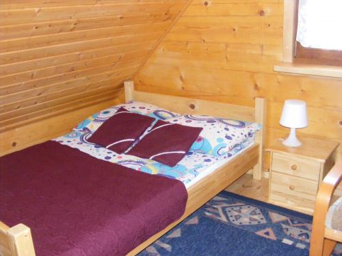 a small bedroom with a bed in a wooden room at Dom letniskowy ANTOLEK in Ryn