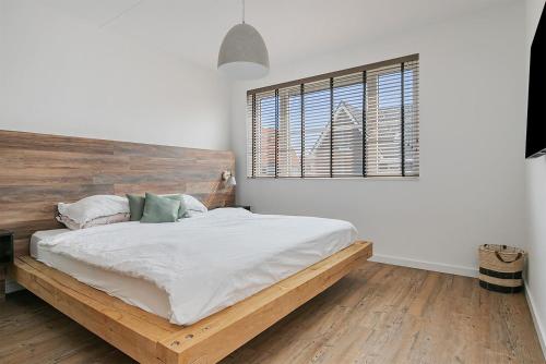 a bedroom with a bed with a wooden headboard and a window at Vakantiehuis - Albert Aylerstraat 10 - Middelburg in Middelburg