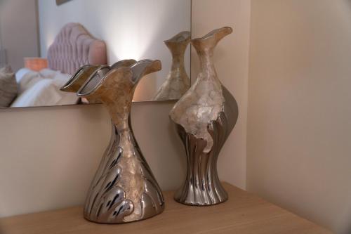 three metal vases sitting on a shelf next to a mirror at Sweet Luxury House in Alepou