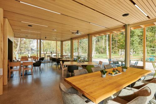 un restaurante con mesas y sillas de madera y ventanas en Apartments am Camping Dornbirn en Dornbirn