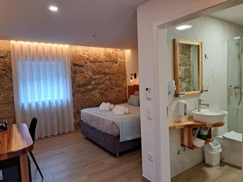 a bedroom with a bed and a bathroom with a sink at Agrafonte in Paços de Ferreira