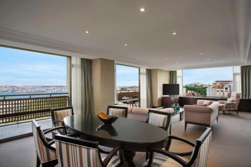 a living room with a table and chairs with a view at Hilton Istanbul Bosphorus in Istanbul