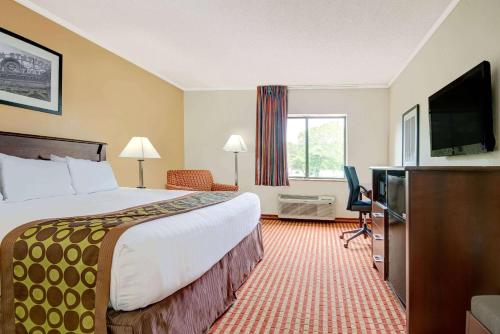 a hotel room with a bed and a flat screen tv at Days Inn & Suites by Wyndham Kansas City - Royals Stadium in Kansas City