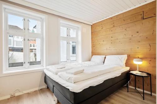 a large bed in a room with two windows at Central first floor apartment in Bergen
