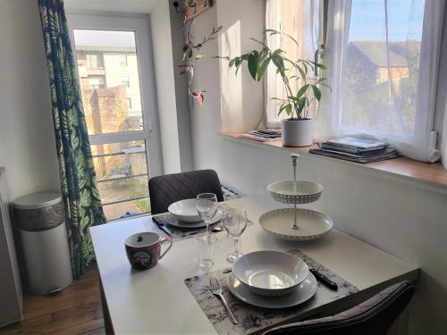 a table with glasses and plates on it in front of a window at Appartement T2 "JUNGLE" Centre Ville de VITRÉ au calme coté cour in Vitré