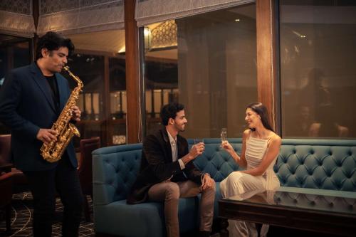 a man playing a saxophone and a woman sitting on a couch at Radisson Collection Hotel & Spa, Riverfront Srinagar in Srinagar
