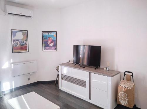 - un salon avec une télévision au-dessus d'une commode dans l'établissement Résidence Le Cendre, à Juan-les-Pins