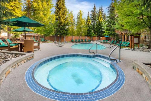 a hot tub in a patio with a table and chairs at Hilton Grand Vacations Club Whistler in Whistler