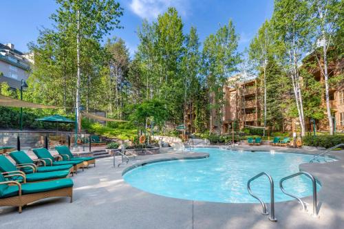 a swimming pool with lounge chairs and a patio at Hilton Grand Vacations Club Whistler in Whistler